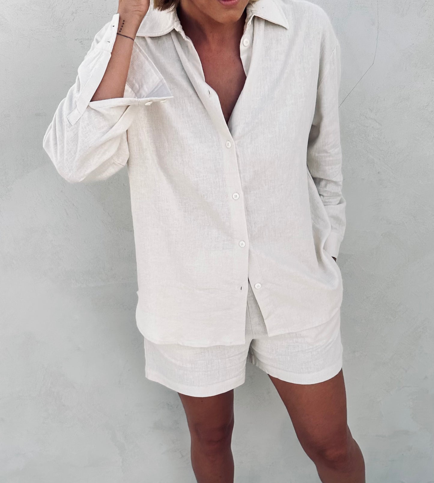 A woman wearing ivory linen Tulua shirt and shorts.