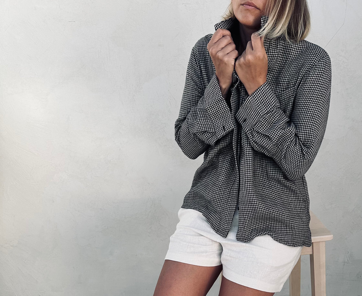 A woman wearing grey linen shirt and white shorts.