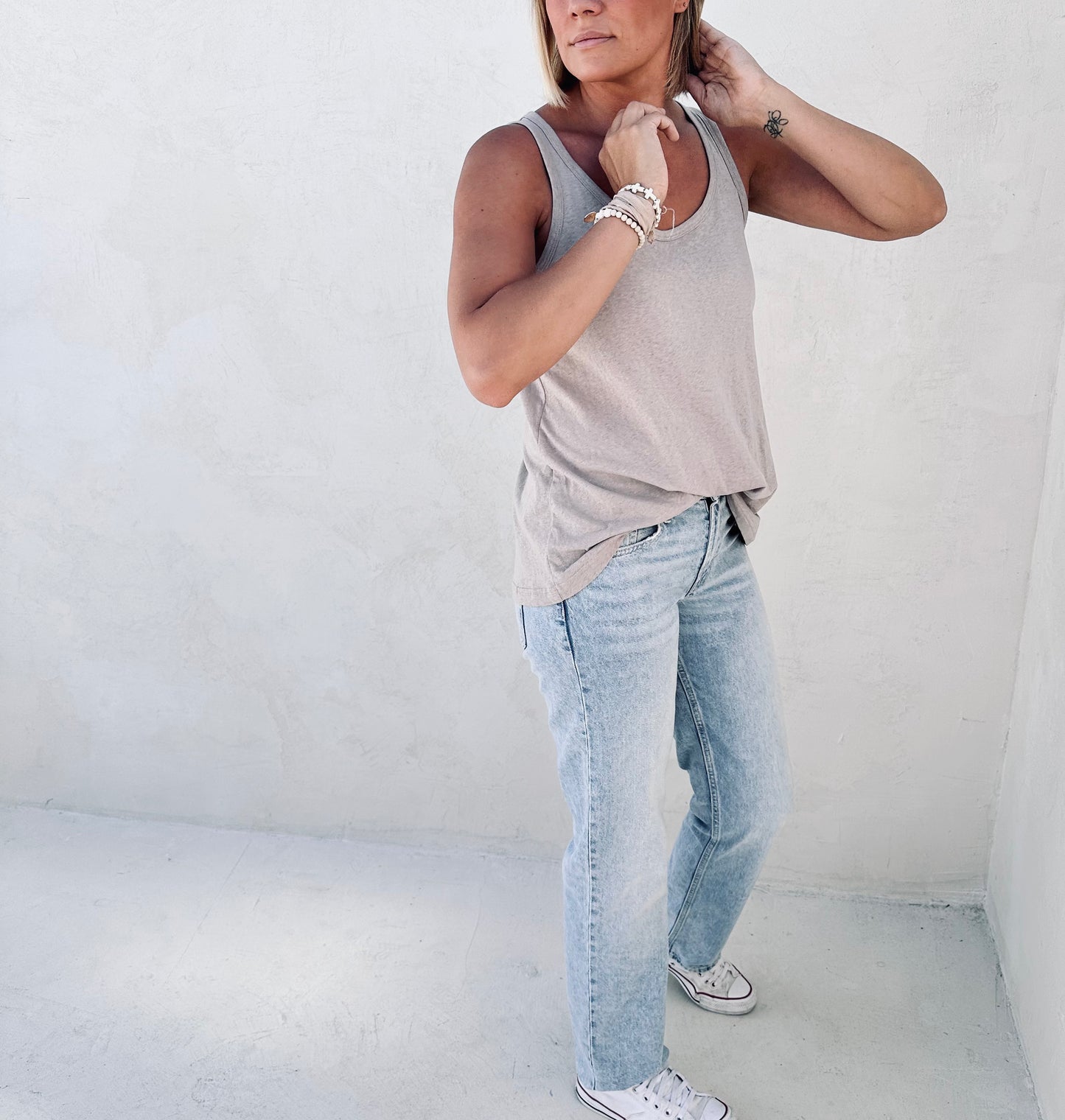 A woman wearing jeans and tulua light taupe tank top.