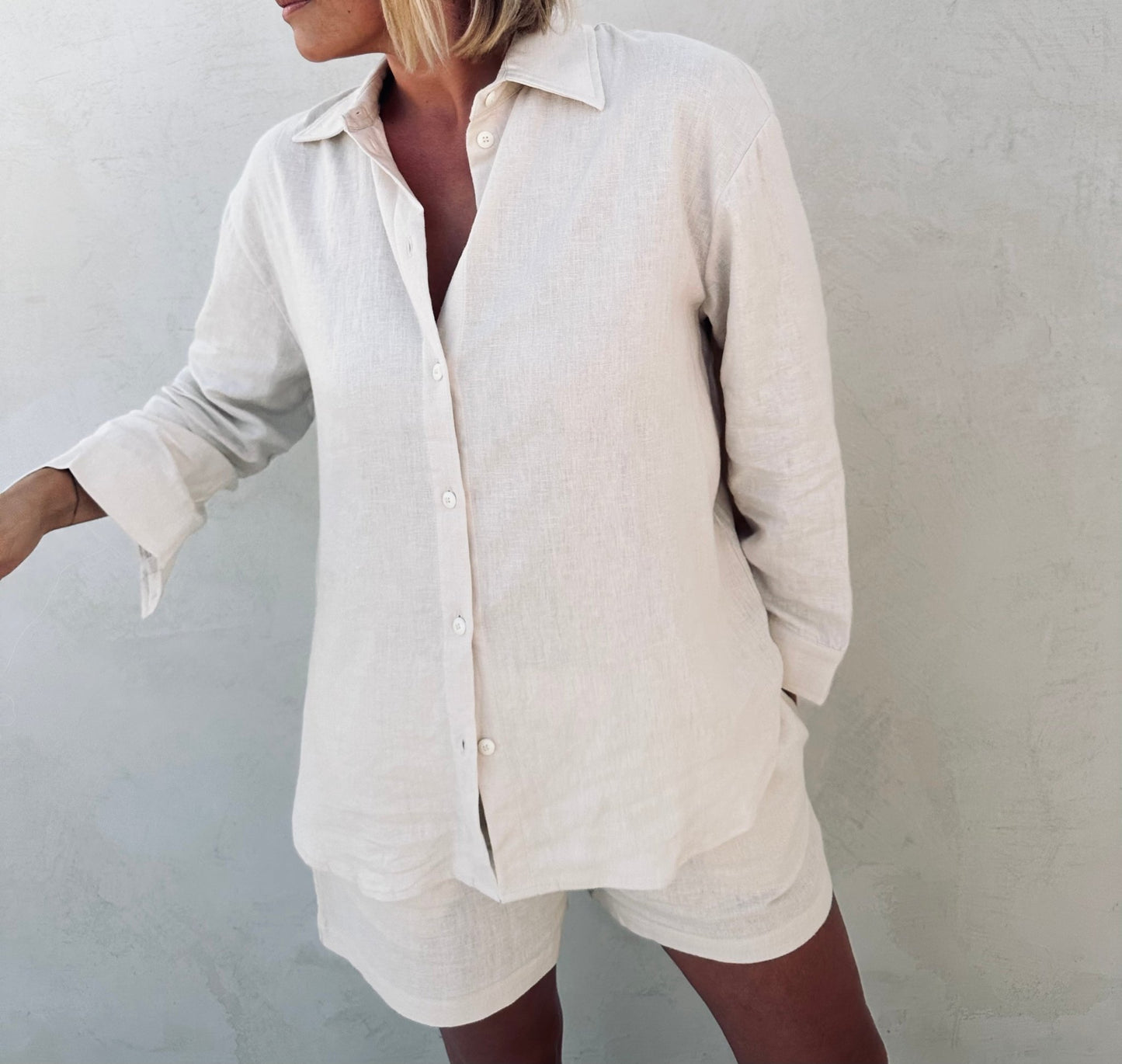 A woman wearing ivory linen shirt and shorts.