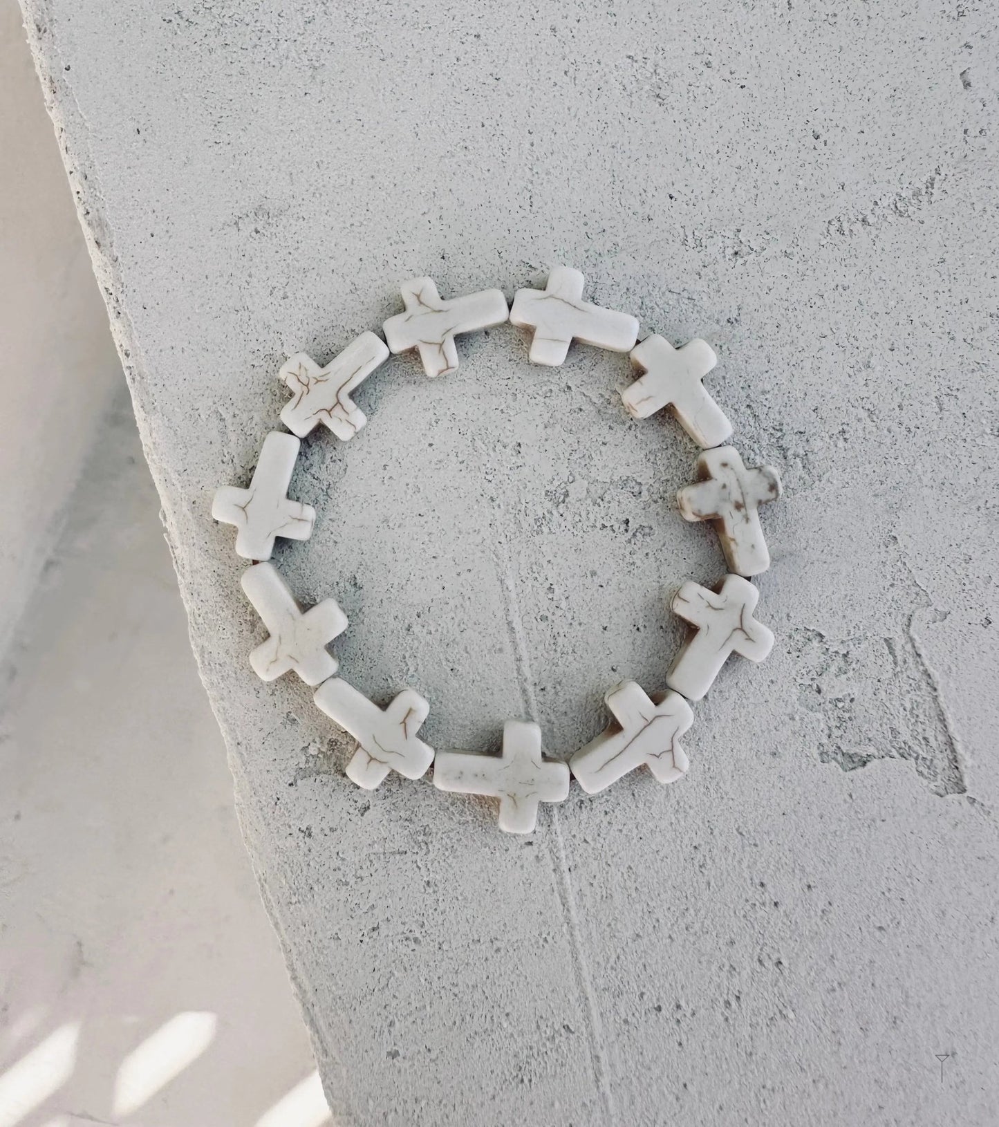 A white bracelet with a crosses around.