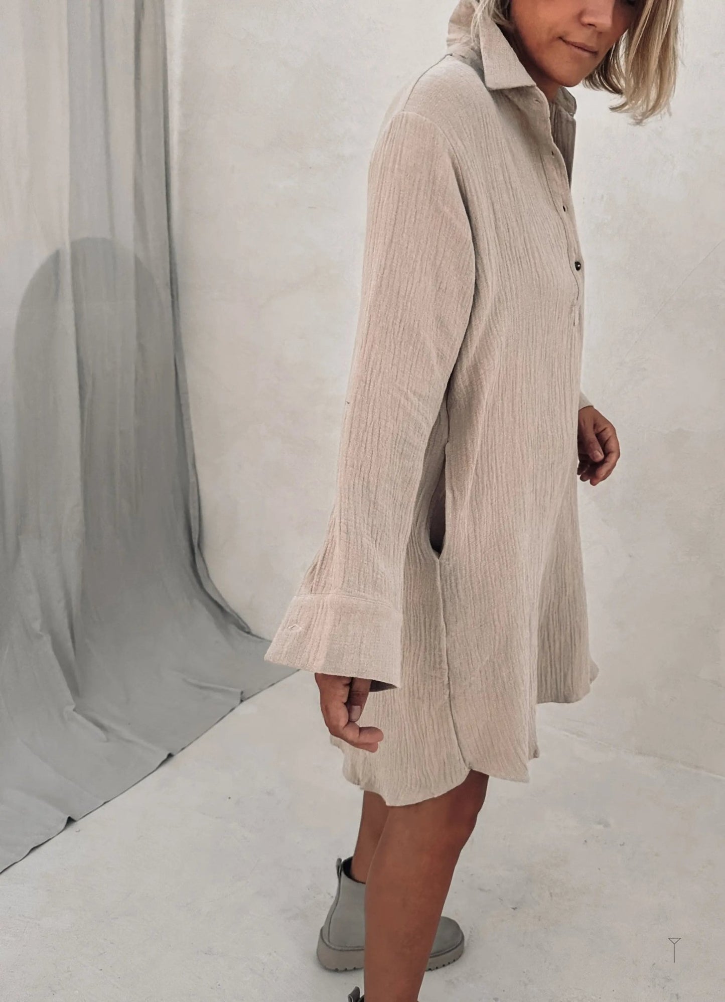 A woman wearing a beige long sleeve dress and grey boots.