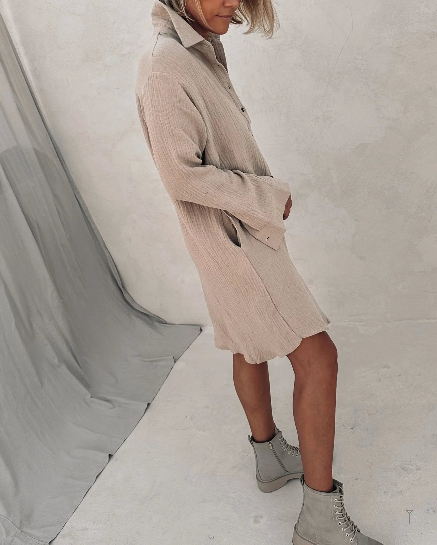 A woman wearing a beige shirt dress and a grey boots.