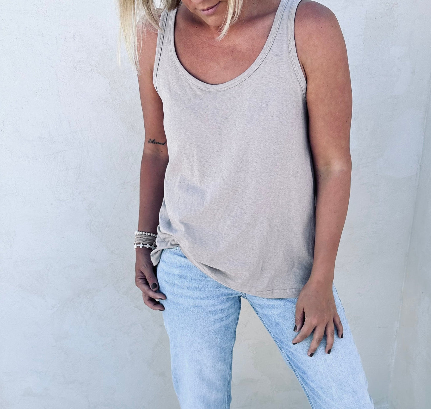 A woman posing for a picture in a taupe tank top.