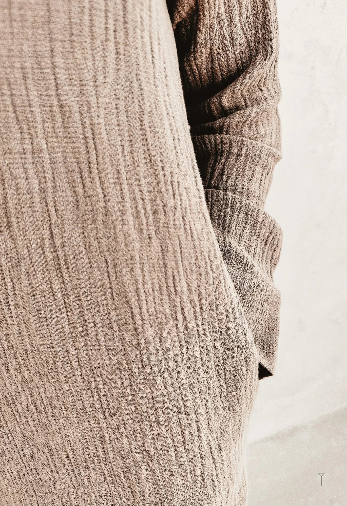 A close up of a woman wearing a beige shirt dress from wrinkle fabric.