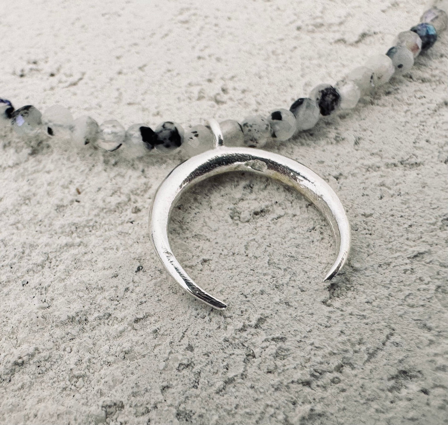 Silver moon necklace with a small stones.