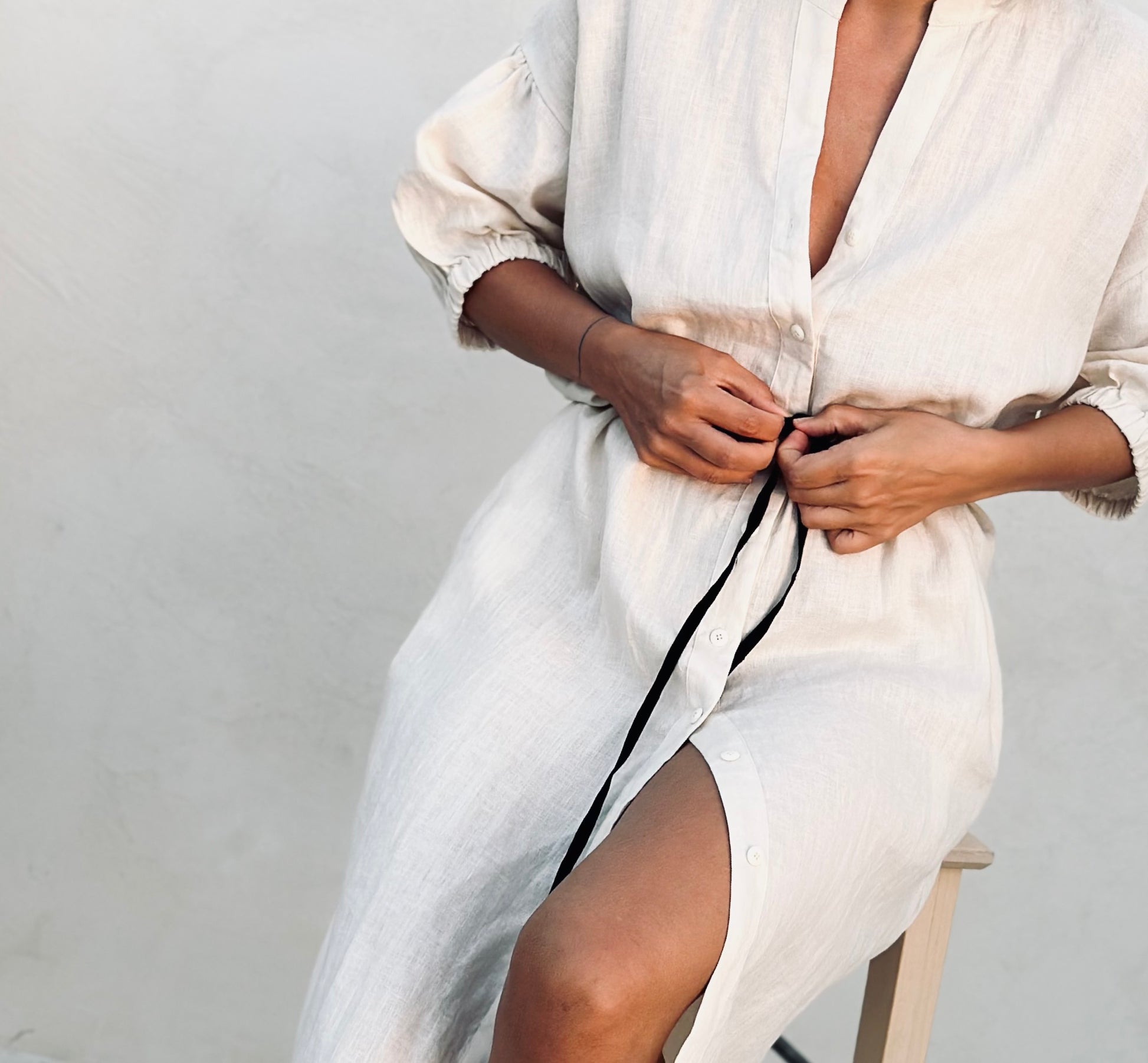 A woman in a white midi shirt linen dress. 