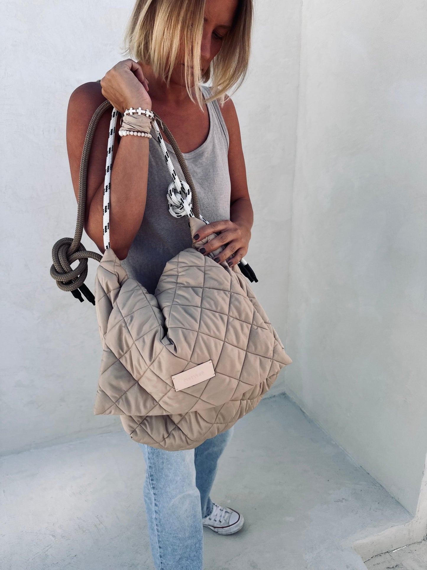 A woman holding a beige quilted bag.  