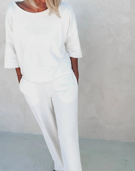 A woman wearing white pants and a white top